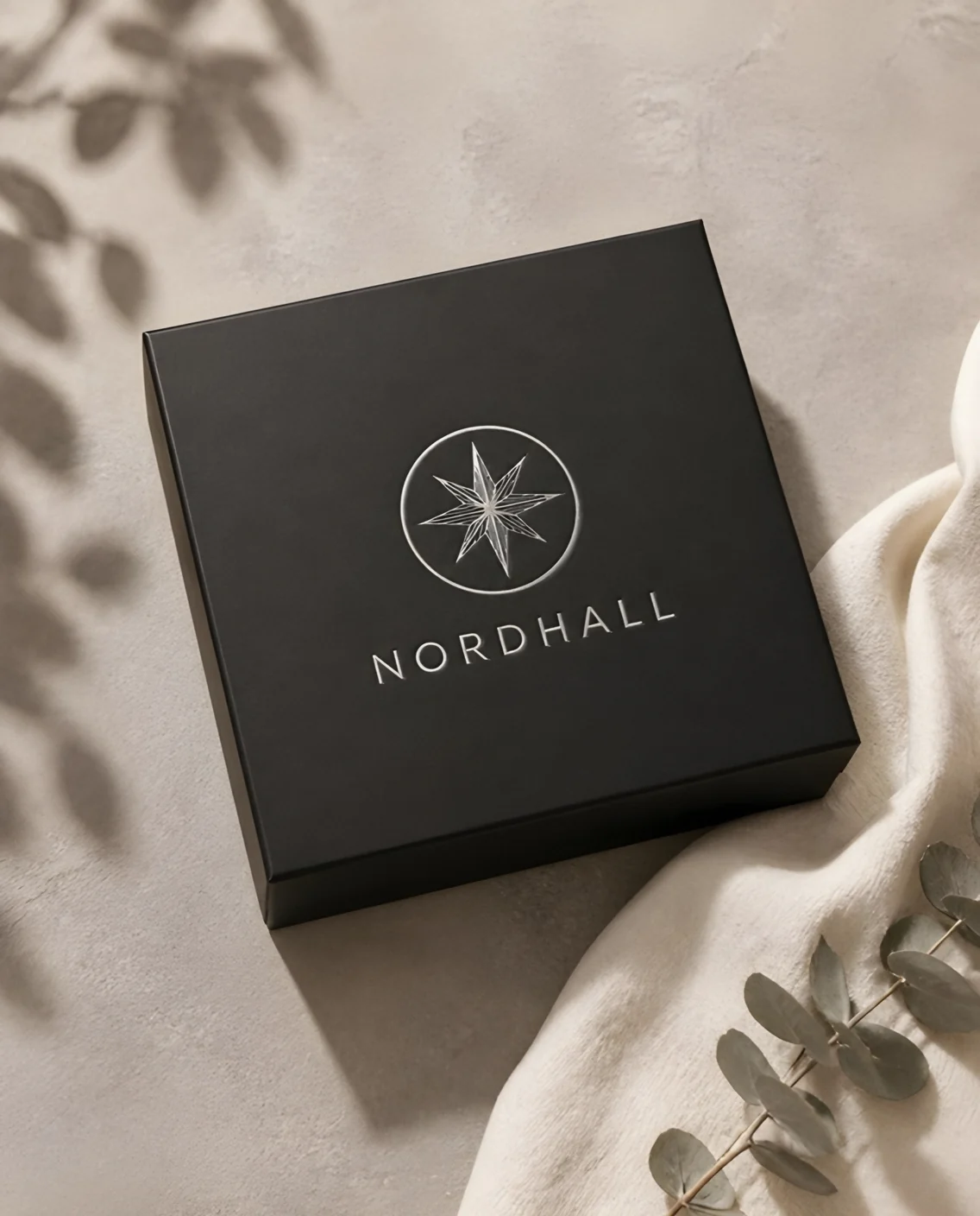 Geschlossene schwarze Stülpdeckelbox mit Logo und Schriftzug in Silber-Heißfolie auf dem Deckel