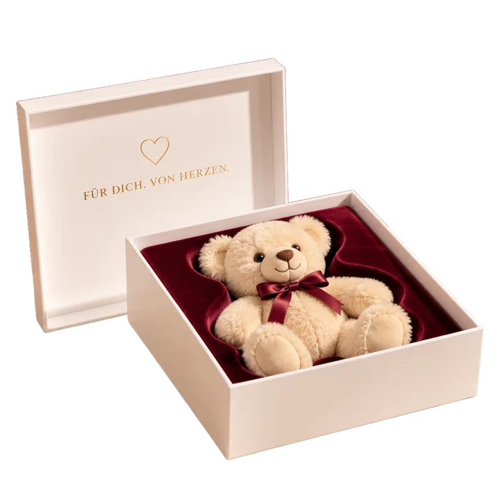 Geöffnete weiße Geschenkbox mit Plüschbär in bordeauxroter Samt-Einlage, im Deckel „Für dich. Von Herzen.“ in Goldfolie