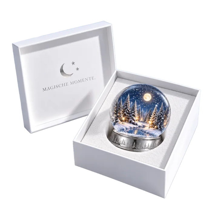 Geöffnete weiße Geschenkbox mit Schneekugel auf weißer Einlage, im Deckel Mond, Sterne und „Magische Momente.“ in Silberfolie