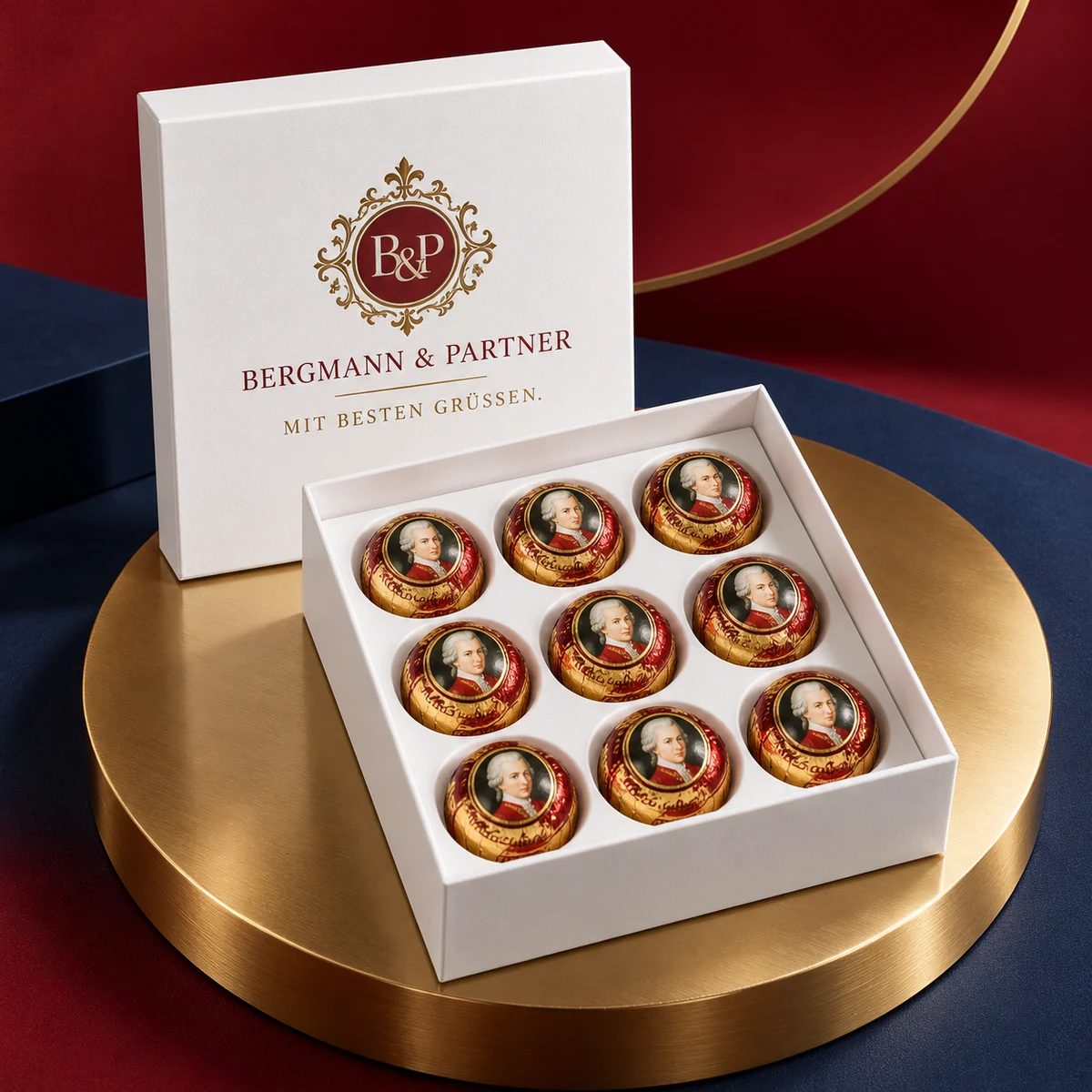 Weiße Stülpdeckelbox mit neun Mozartkugeln, im Deckel Firmenmonogramm und „Mit besten Grüßen.“